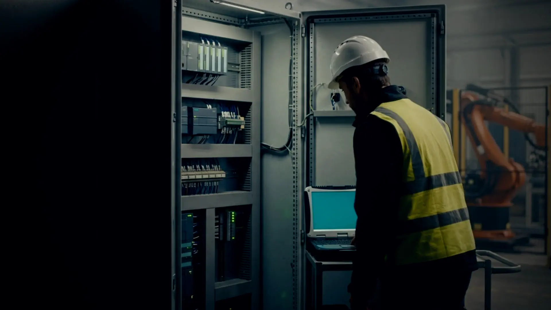 Controls engineer at a row of open control cabinets during a night shutdown
